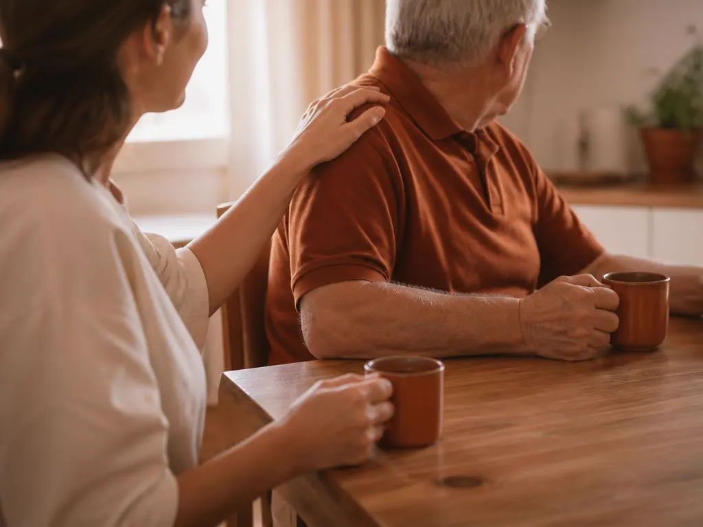 Caffè condiviso al tavolo di cucina con una mano sulla spalla